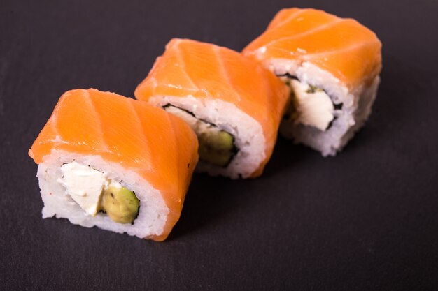 Philadelphia Kalifornien Sushi-Rollen liegen auf schwarzer Keramikplatte