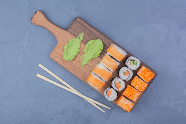 Philadelphia, Lachs und Sake Maki Brötchen mit Wasabi auf einer Holzplatte.