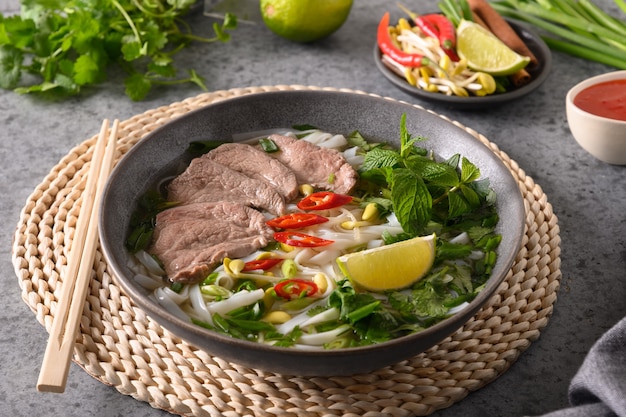 Pho bo suppe mit rindfleisch in grauer schüssel auf grauer vietnamesischer küche Premium Fotos