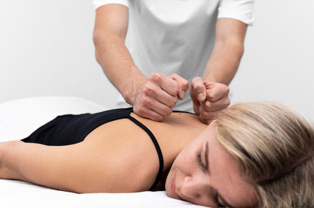 Physiotherapeut, der Rückenmassage auf Frau durchführt