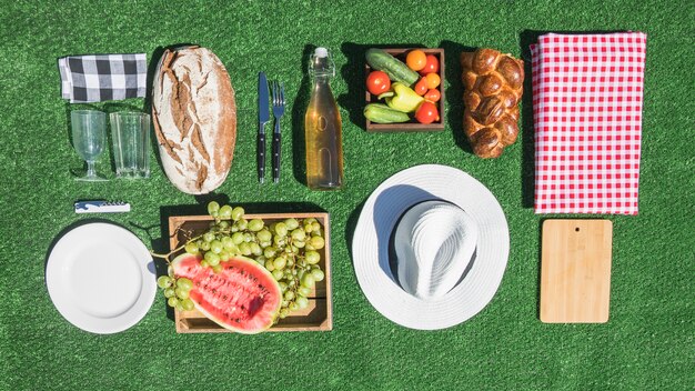 Picknick Essen; Brot; Früchte; Teller; Hackbrett; Tischdecke auf grünem Rasen