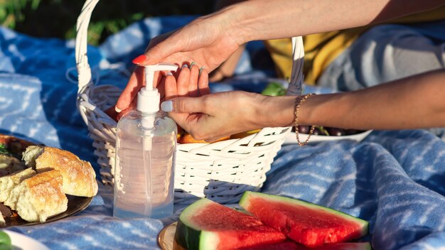 Picknickdecke mit Leckereien und Desinfektionsmittel für die Hände