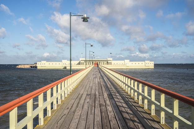 Kostenloses Foto pier umgeben von meer und gebäuden unter bewölktem himmel und sonnenlicht