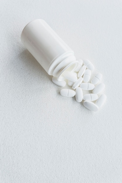 Pillen, die heraus von der weißen Plastikflasche heraus verschüttet werden