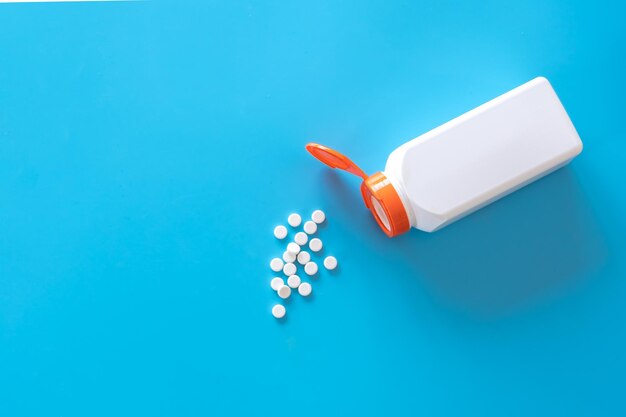 Pillen werden aus einem Glas auf blauem Hintergrund flach gelegt