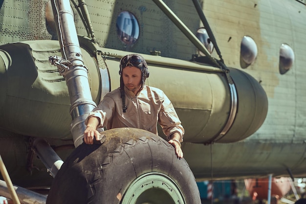 Pilot oder Mechaniker in Uniform und fliegendem Helm wäscht großen Militärhubschrauber.