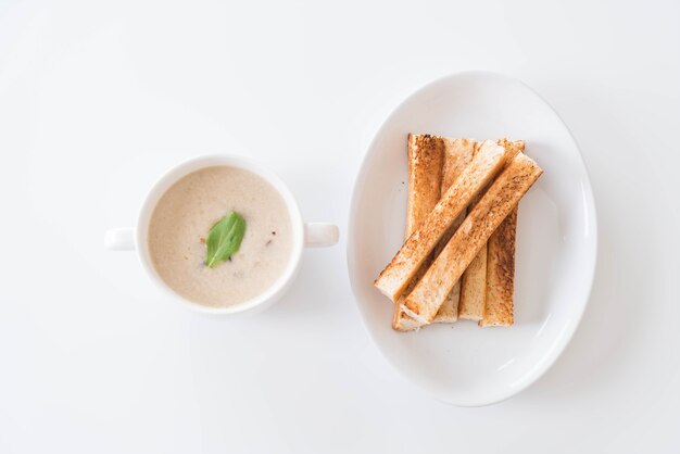 Pilzsuppe und Brot in weissem Keramikbecher