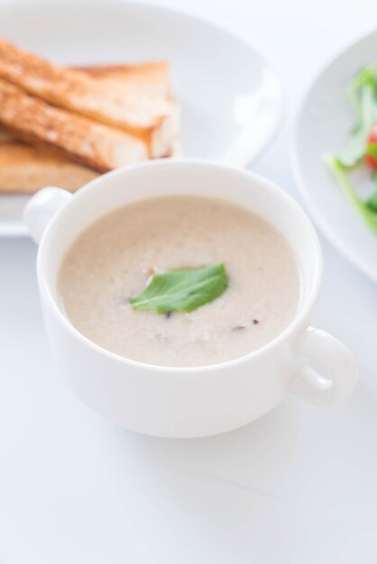 Pilzsuppe und Brot in weissem Keramikbecher