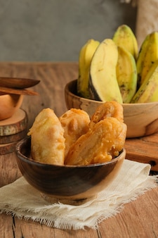 Pisang goreng serviert auf holztisch. ist beliebtes streetfood in südostasien, insbesondere in malaysia und indonesien. hergestellt aus gebratener banane mit süßem teig überzogen Premium Fotos
