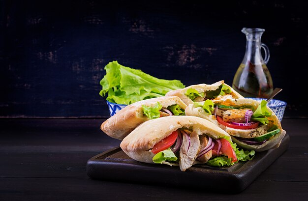 Pita gefüllt mit Huhn, Tomate und Salat auf Holztisch. Nahöstliche Küche.