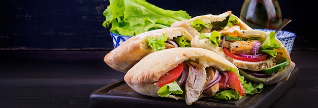 Pita gefüllt mit Huhn, Tomate und Salat auf Holztisch. Nahöstliche Küche.