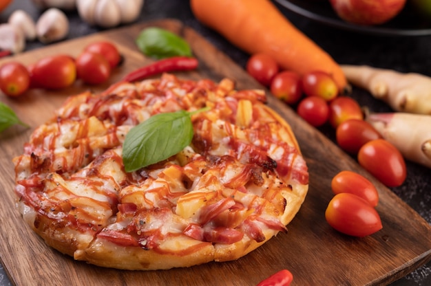 Pizza in einem Holztablett mit Tomaten Chili und Basilikum.