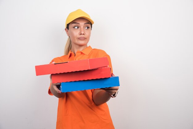 Pizza-Lieferfrau, die Pizzaschachteln mit friedlichem Gesicht auf weißem Hintergrund hält.