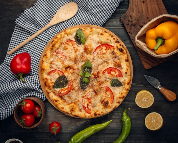 Pizza mit grünen Basilikum- und Tomatenscheiben.