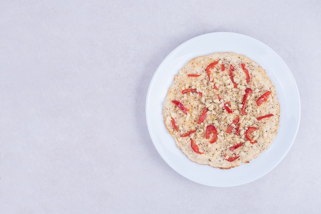 Pizza mit Paprika auf Holzteller auf Weiß