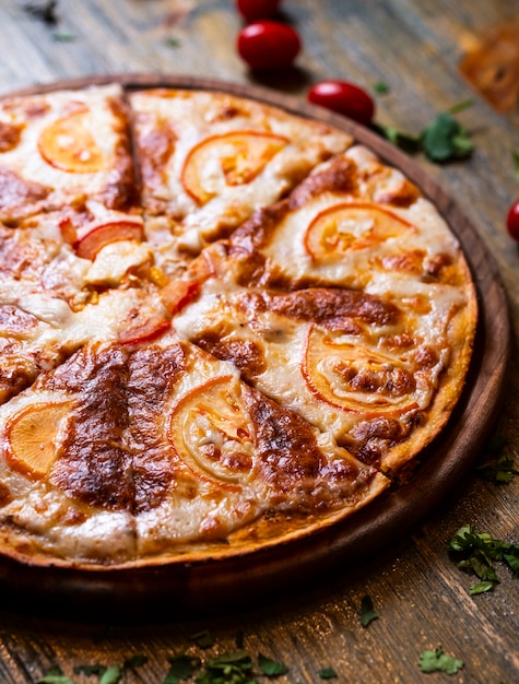 Pizza mit Tomaten auf Holzschreibtisch