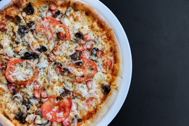 Pizza mit Würstchen, Tomaten, Käse, Oliven und Pfeffer