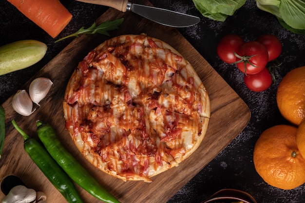 Pizza mit Wurst, Mais, Bohnen, Garnelen und Speck auf einem Holzteller