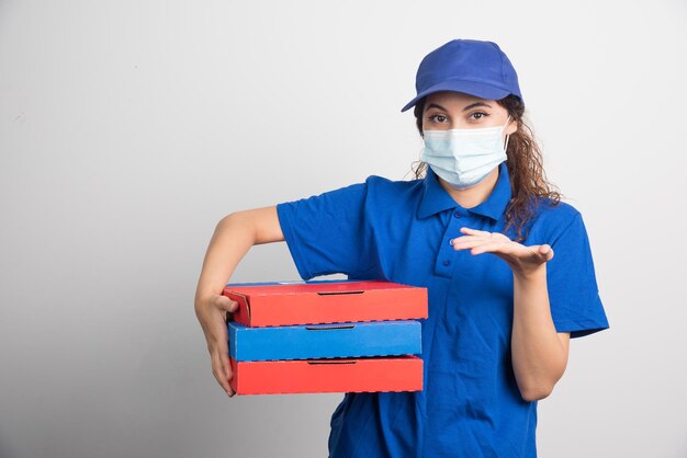 Pizzalieferant, der drei Kisten mit medizinischer Gesichtsmaske auf Weiß hält