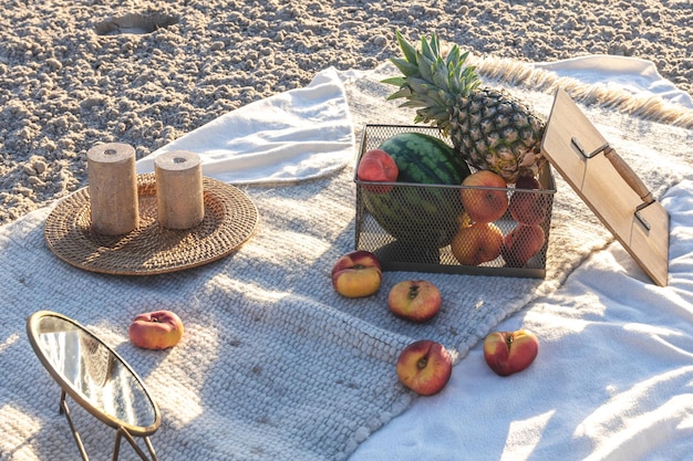 Plaid mit Früchten auf dem Picknick an der sandigen Küste am Meer