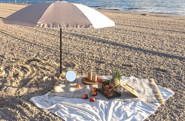 Plaid mit Früchten auf dem Picknick an der sandigen Küste am Meer