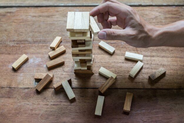 Planung, Risiko und Strategie in der Wirtschaft, Geschäftsmann und Ingenieur Glücksspiel Platzierung Holz Block auf einem Turm.