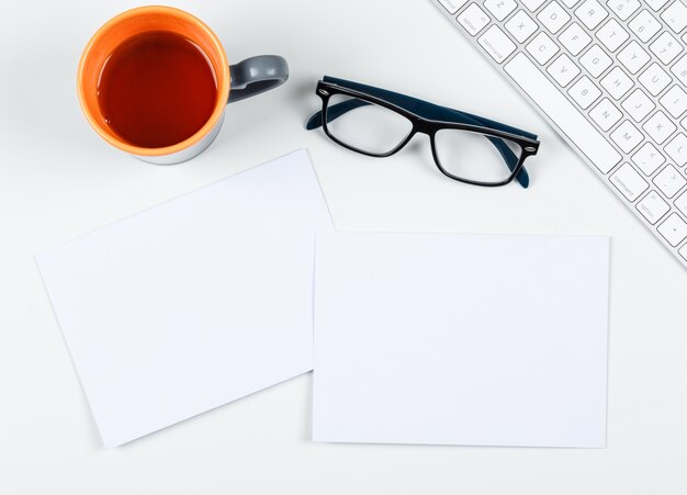 Planungskonzept mit einer Tasse Tee, Brillen, Papier, Tastatur auf weißem Hintergrund, Platz für Text, Draufsicht. horizontales Bild