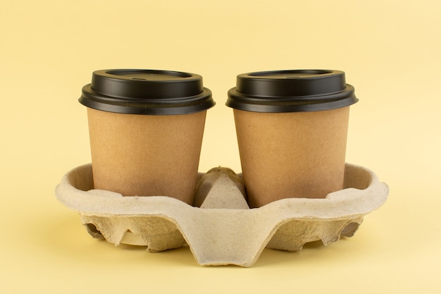 Plastikkaffeetassen der Vorderansicht liefern Kaffee auf dem gelben Tischkaffeegetränklieferung
