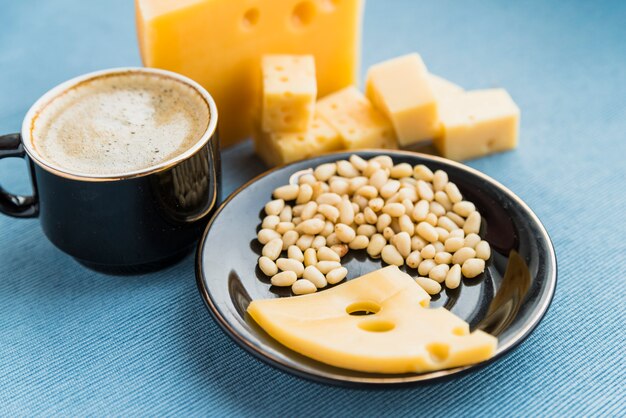 Platte mit Frischkäse und Nüssen nahe Schale des Getränks auf Tabelle