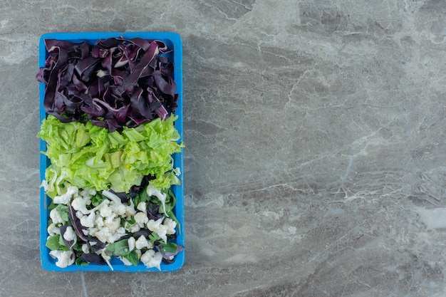 Platte mit gehacktem Kohl, Blumenkohl und Amaranth auf Marmor.