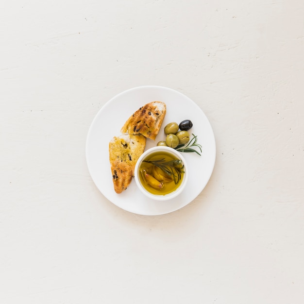 Platte mit Scheibe Brot Öl und Oliven