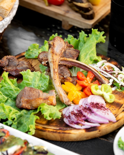 Platte mit Tikka-Kebab, serviert mit Zwiebelscheiben, Gemüse und Salat