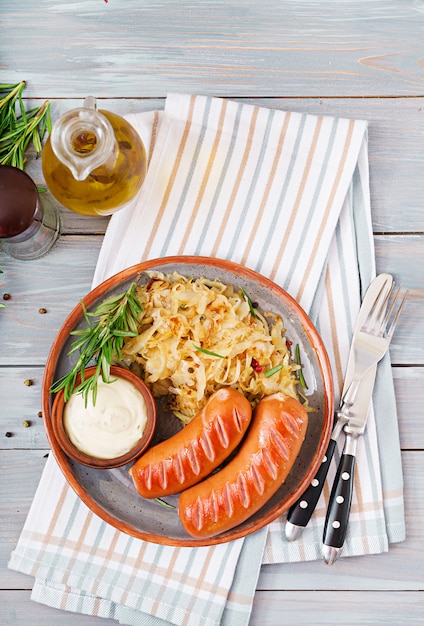 Platte von Würsten und von Sauerkraut auf Holztisch. Traditionelles Oktoberfest-Menü. Flach liegen. Ansicht von oben.