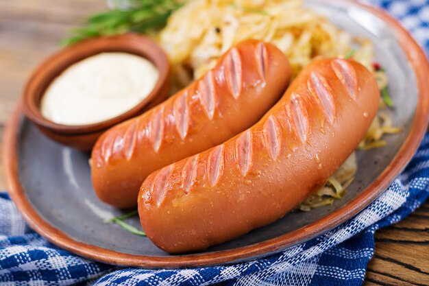 Platte von Würsten und von Sauerkraut auf Holztisch. Traditionelles Oktoberfest-Menü