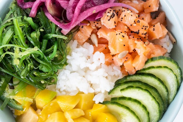 Poke Bowl mit Reislachsgurkemangoonionwakame Salatmohn und Sonnenblumenkernen isoliert auf weißem Hintergrund