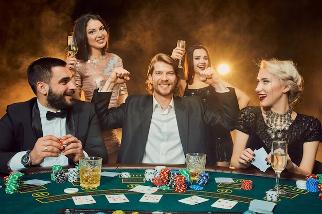 Kostenloses Foto pokerspieler sitzen um einen tisch in einem casino. poker. glücksspiel. kasino