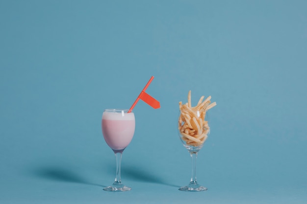 Pommes-Frites in einem Weinglas neben einem rosa Getränk