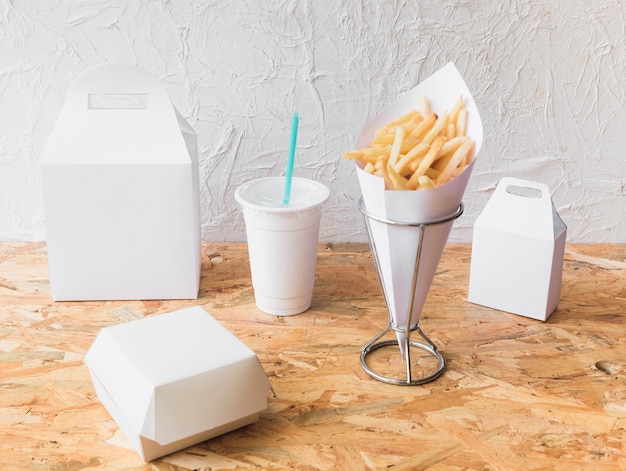 Kostenloses Foto pommes frittes; wegwerfschale und lebensmittelpaketspott oben auf hölzernem beschaffenheitshintergrund