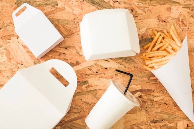 Pommes frittes; Wegwerfschale und -pakete auf hölzernem Hintergrund