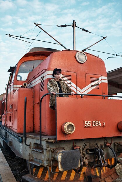 Pop-Punk-ästhetisches Porträt einer Frau, die an einer Lokomotive posiert