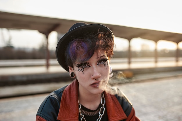 Kostenloses Foto pop-punk-ästhetisches porträt einer frau, die im bahnhof posiert