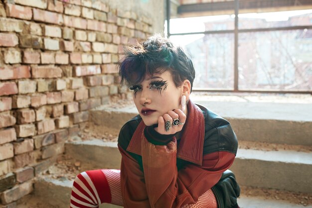 Pop-Punk-ästhetisches Porträt einer Frau, die im Inneren des Gebäudes auf der Treppe posiert