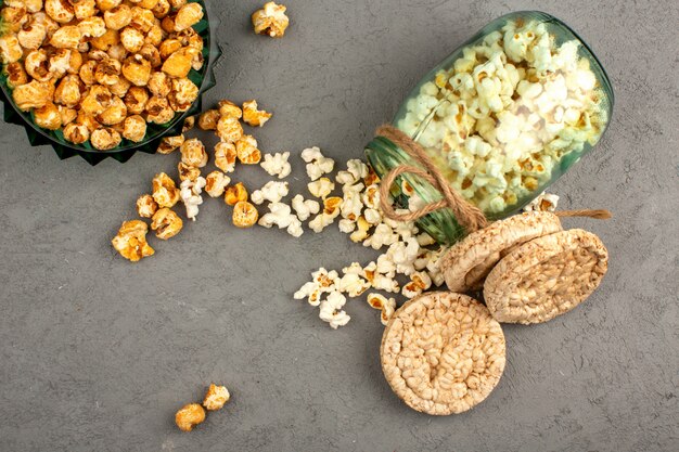 Popcorn süß und gesalzen zusammen mit Brotkeksen auf einem grauen Boden verteilen