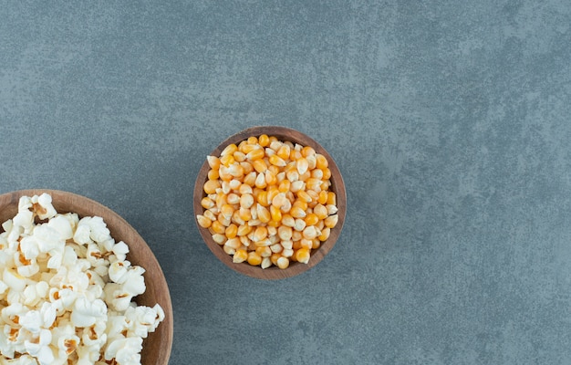 Popcorn- und Maiskörner in Schalen auf Marmorhintergrund gefüllt. Foto in hoher Qualität