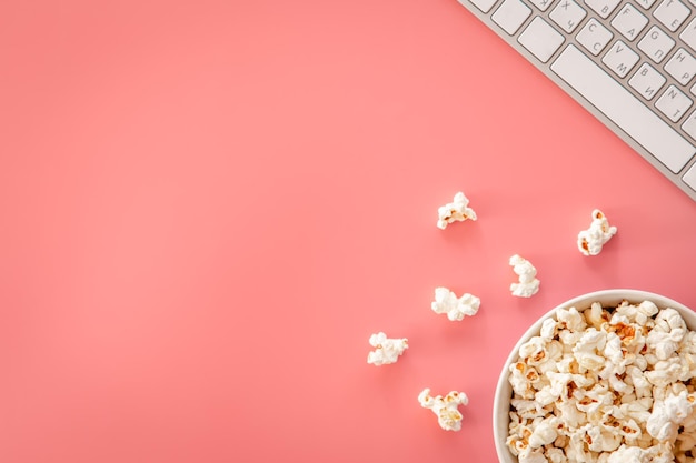 Kostenloses Foto popcorn und tastatur auf rosa hintergrund flach gelegt