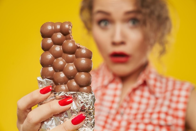 Poröse Milchschokolade in der Hand eines Mädchens mit roten Nägeln