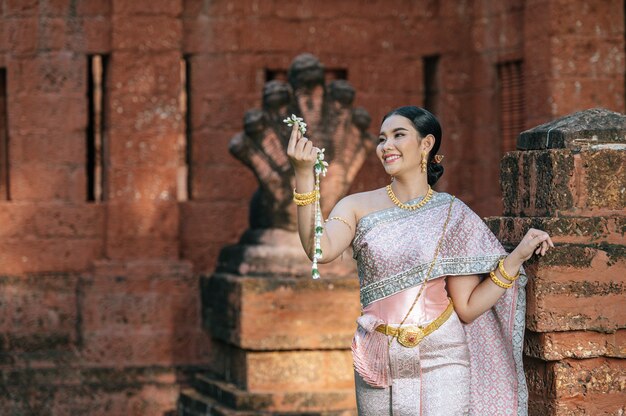 Porträt asiatische charmante Frau mit schöner typischer thailändischer Identitätskultur Thailands in einem alten Tempel oder einem berühmten Ort mit anmutiger Pose