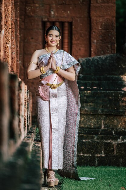 Porträt asiatische charmante Frau mit schöner typischer thailändischer Identitätskultur Thailands in einem alten Tempel oder einem berühmten Ort mit anmutiger Pose