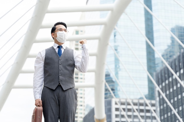 Porträt asiatischer Geschäftsmann, der schützende Gesichtsmaske zum Schutz während der Quarantäne trägt