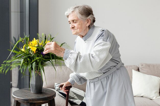 Porträt der älteren Großmutter, die Blumen berührt
